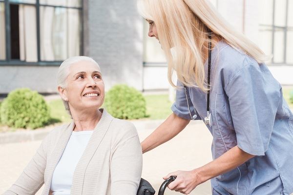 nurse helping elderly woman in a wheelchair