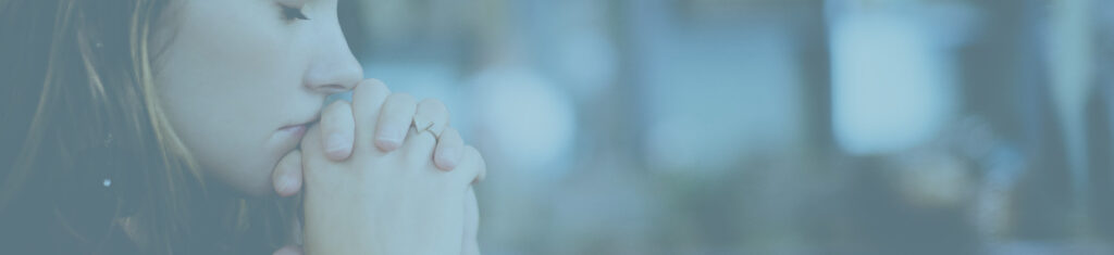 Close up of a woman with hands folded together praying or thinking