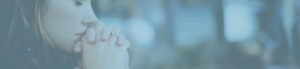 Close up of a woman with hands folded together praying or thinking
