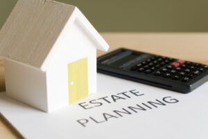 Cell phone and toy house on top of piece of paper that reads Estate Planning