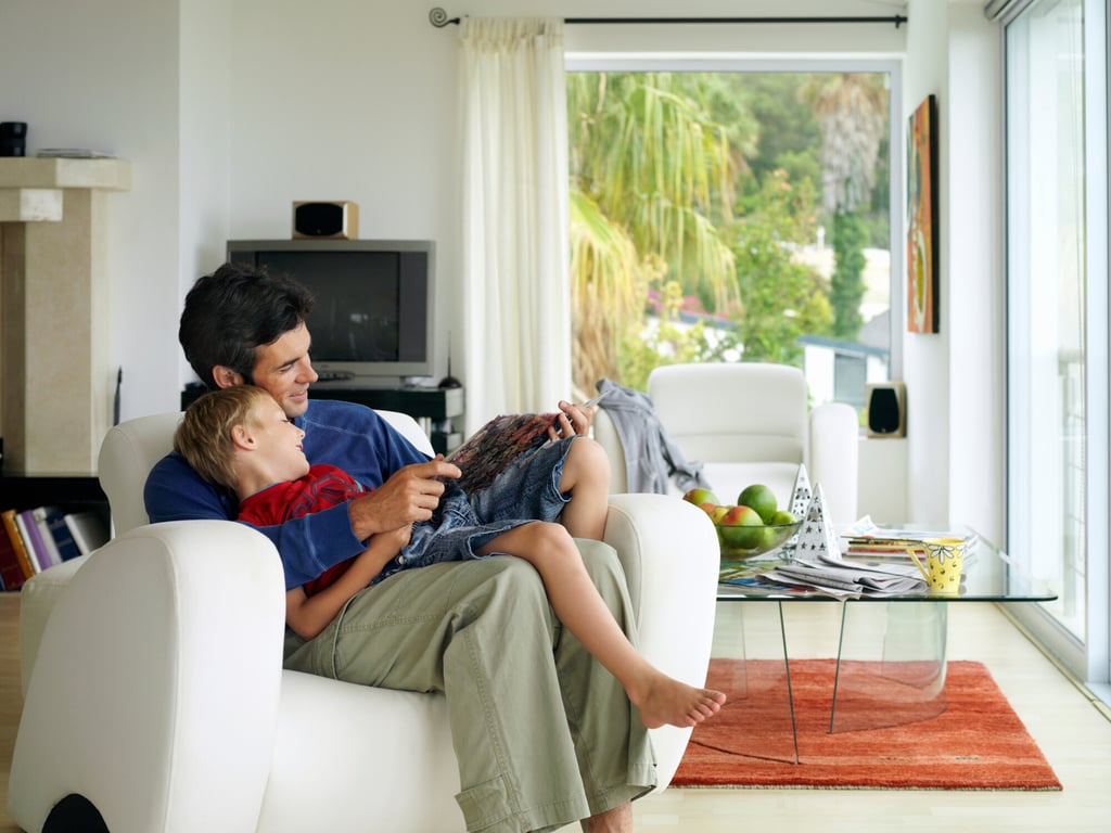 Dad and son sitting in chair reading a book together