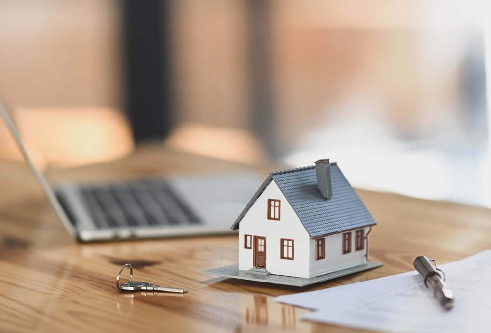 Laptop, papers, pen, and a miniature house sitting on a desk Probate process