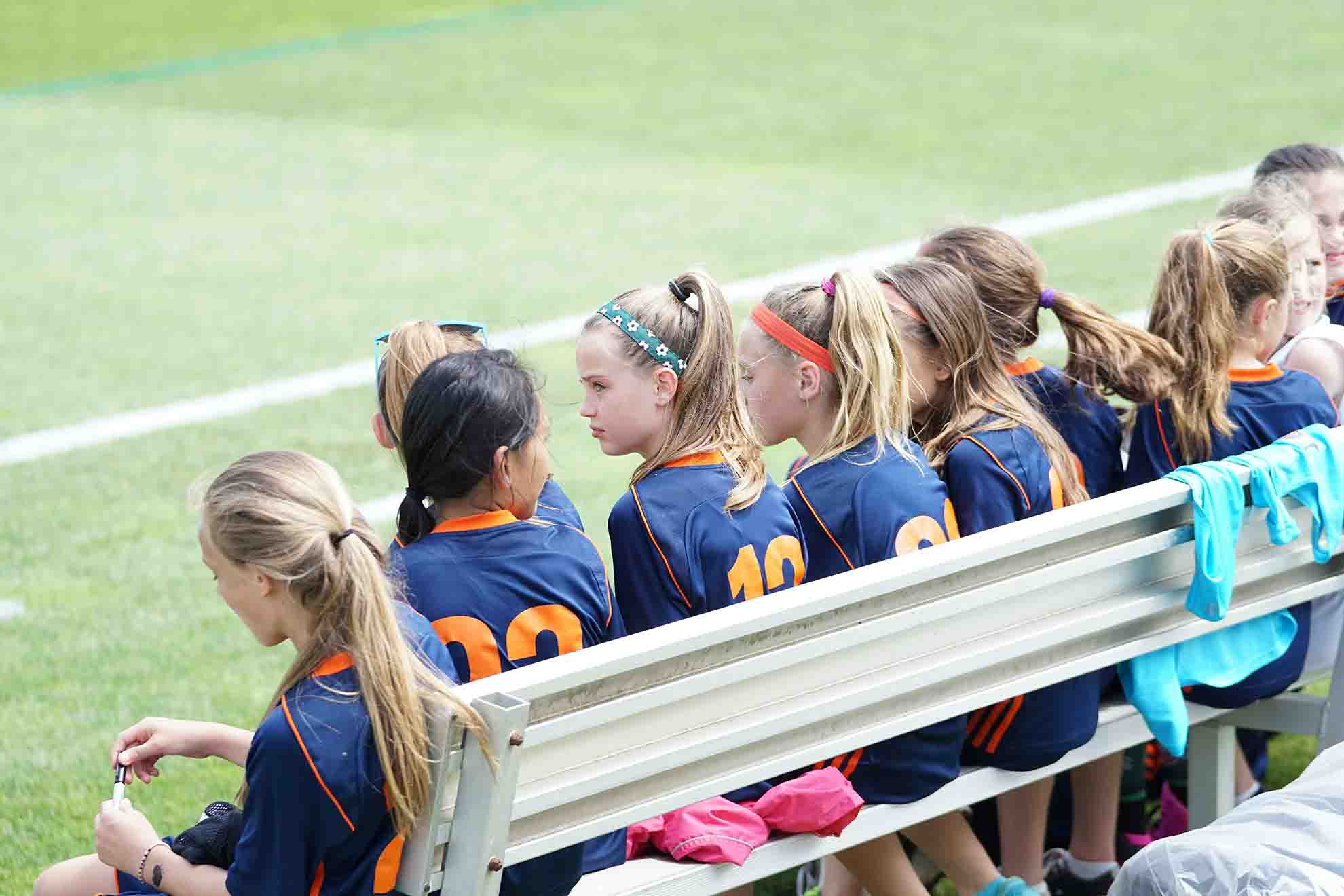a team of girl soccer players sitting on the bench