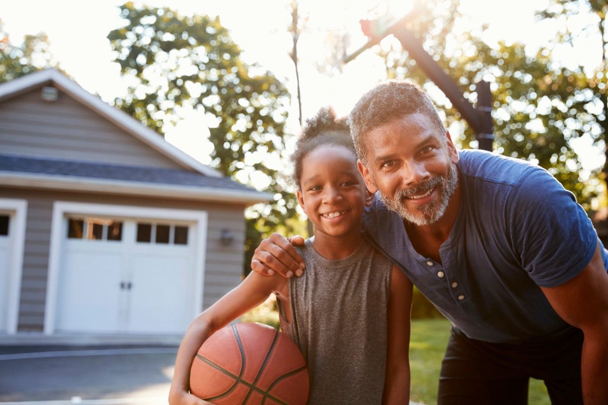 Black father and young daughter playing basketball posing and smiling
