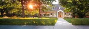 Nice home with trees and trimmed hedge along sidewalk