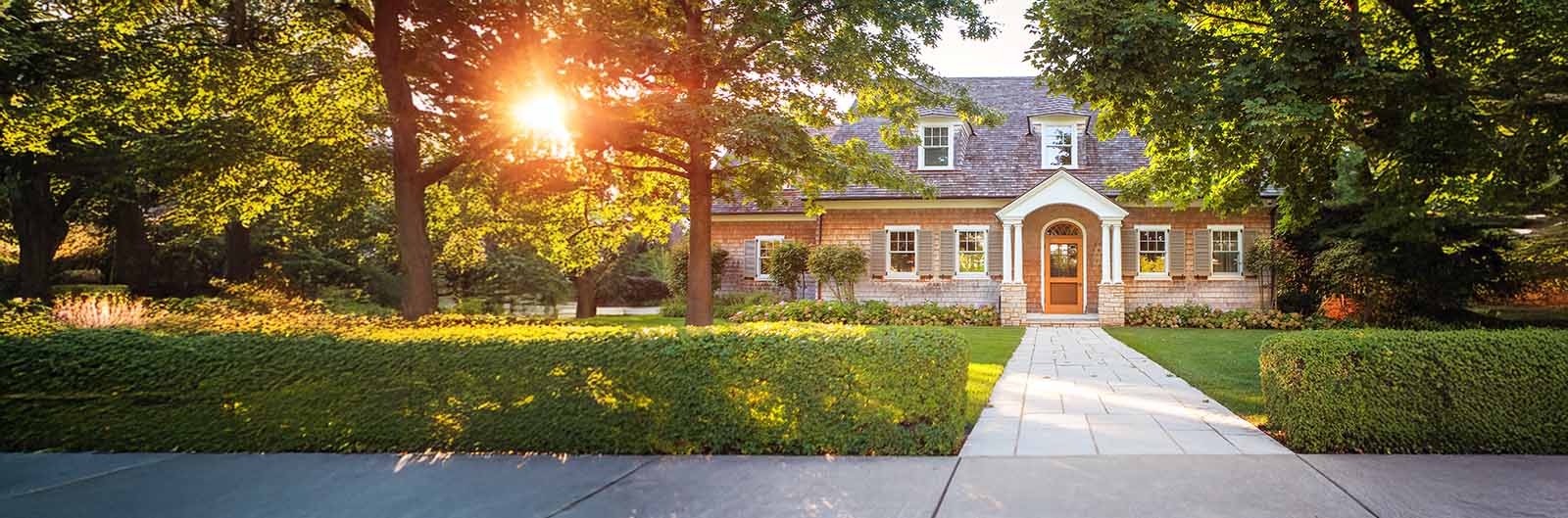 Nice home with trees and trimmed hedge along sidewalk