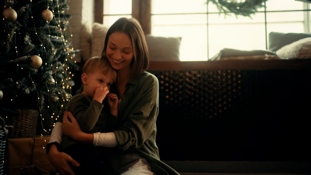 Mom holidng young son seated infront of holiday tree