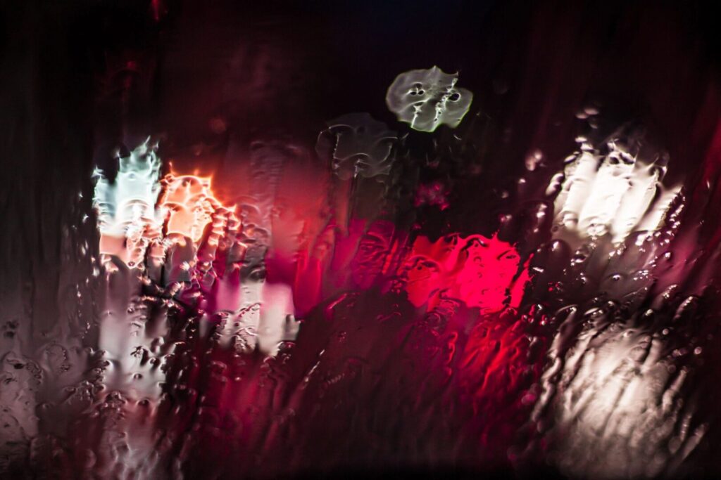 lights shinning through rain soaked glass