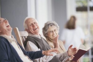 older people smiling while seated in rocking chairs