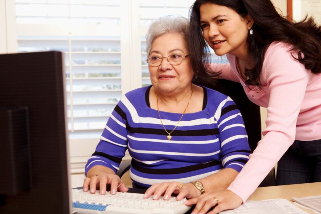 younger woman helping older one with computer work