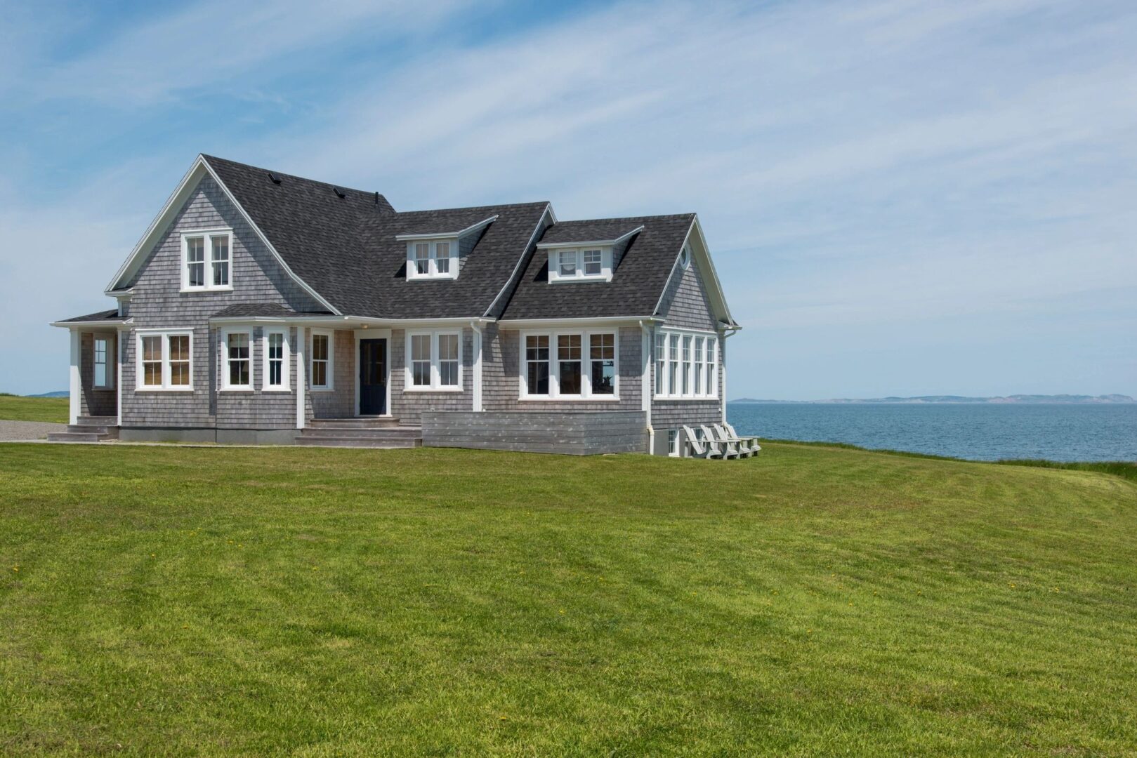 blue house set in front of water with green grass